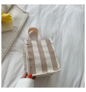 Détail du mini sac en toile portable à rayures brunes sur un tissu doux