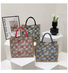 Three woven plaid tote bags in red blue and black displayed on geometric stands