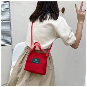 Detail of red canvas bucket bag with green label shown on model for casual wear