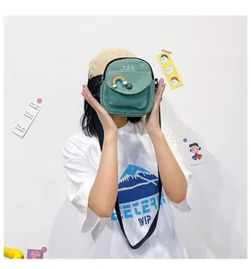 Detail of dark green canvas crossbody bag featuring rainbow patch and adjustable strap