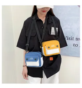 Detail of canvas crossbody bag with KOQ logo and adjustable strap on a female model