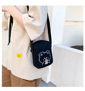 Detalle del bolso bandolera de lona negra con un lindo oso de dibujos animados y boba