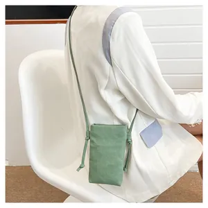 Detail van de lichtgroene canvas mini crossbody telefoontas op een casual blazer model
