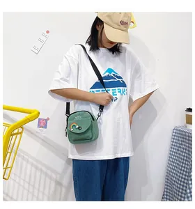 Detail of green canvas crossbody bag featuring rainbow embroidery and adjustable strap