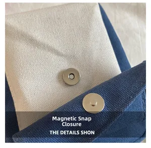 Detail shot of the metal magnetic closure on a beige and navy canvas shoulder bag