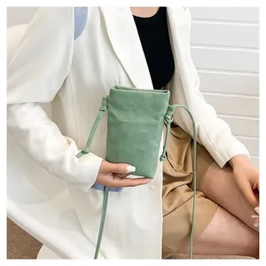Detail van een groene mini canvas crossbody tas met verstelbaar koord op een model