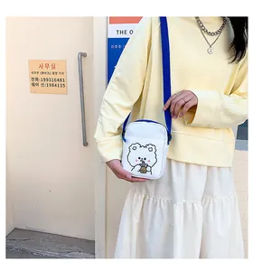 Detalle de mini bolso bandolera de lona con oso animado llevado por una modelo joven
