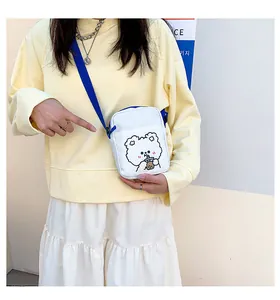 Detalle del bolso bandolera de lona blanca con oso de dibujos animados y correa azul