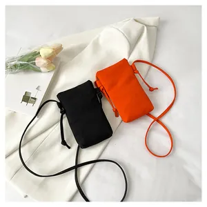 Platliggende weergave van mini canvas telefoontassen in zwart en oranje op een blazer