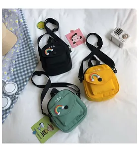 Detail of mini canvas crossbody bags with rainbow patches in black, yellow, and green colors