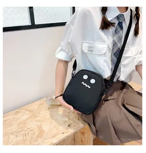 Detail of cute black crossbody bag featuring cartoon face with adjustable shoulder strap