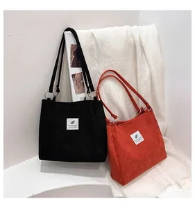 Detail of corduroy tote bags showing fabric texture and silver metal rings on handles
