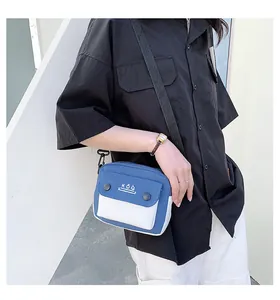 Detail showing the blue and white canvas crossbody bag with adjustable black shoulder strap