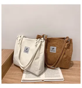 Detailed view of beige and brown corduroy tote bags with metal ring shoulder strap links