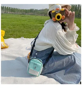 Detail of a green canvas crossbody bag with cute rabbit embroidery on grass background