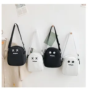Detail view of small canvas crossbody bags with cartoon expressions in black and white