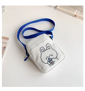 Detalle de bolso bandolera de lona blanca con correa azul y bordado de conejo animado