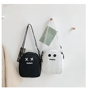 Detail view of black and white canvas mini crossbody bags with cute cartoon expressions