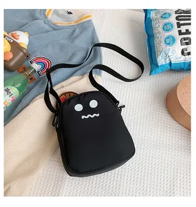 Detail of a black cartoon crossbody bag featuring a cute white monster expression print