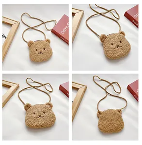 Detail view of brown plush bear crossbody bag with embroidered face and long shoulder strap