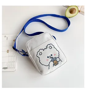 Detalle del bolso bandolera de lona blanca con lindo oso de dibujos animados y correa