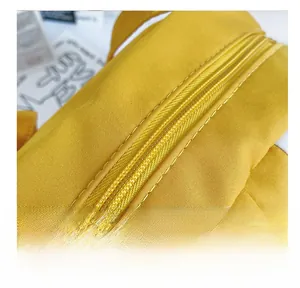 Macro detail of high-quality stitching and metal zipper on bright yellow canvas bag