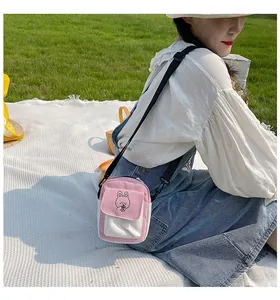Pink and white canvas crossbody bag with cartoon bunny print on a summer picnic cloth