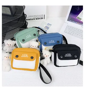 Close-up of colorful canvas crossbody bags with plush bear charms in four vibrant colors