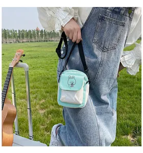 Detail of mint green canvas crossbody bag with cartoon rabbit print and shoulder strap