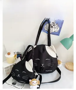 Detail view of black canvas cat-themed tote bag and matching crossbody set with plush pendant