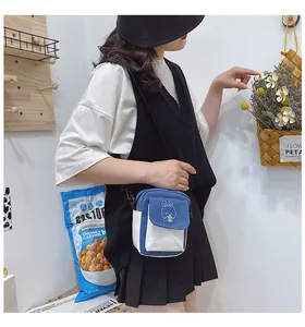 Detail of canvas crossbody bag featuring blue and white stitching with rabbit embroidery