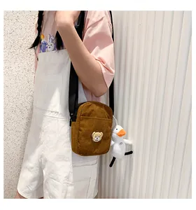 Detail of brown corduroy crossbody bag featuring bear embroidery and duck charm