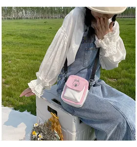 Outdoor shot of a pink and white canvas crossbody bag with a cute cartoon rabbit print