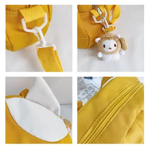 Detail of yellow canvas bag featuring plastic hooks and a cute plush animal pendant