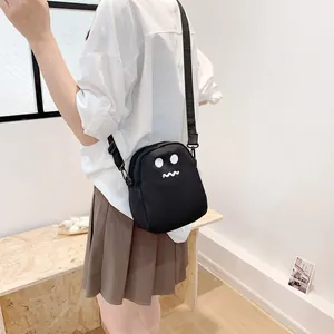 Minimalist black cartoon crossbody bag with white face print and adjustable strap