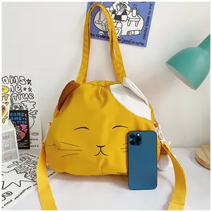 Detail of yellow cat canvas tote with wide strap and phone for size reference