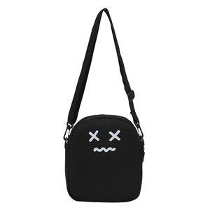 Black canvas crossbody bag with cartoon face print and adjustable shoulder strap