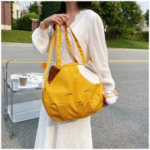 Detail of cute yellow cat canvas tote bag featuring adjustable strap and plush charm