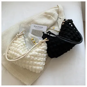 Detailed texture of bubble pleated fabric shoulder bags in cream and black on tweed jacket