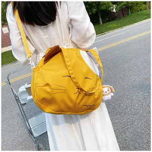 Detail of yellow cat shaped canvas bag with embroidered face and adjustable strap
