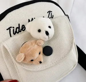 Close-up of white canvas bag with cute 3D plush bear heads and black embroidery detail