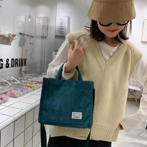 Dettaglio della borsa a mano in velluto a coste verde scuro con trama e etichetta decorativa