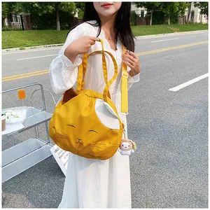 Detail of yellow cat-shaped canvas tote bag with ears and white plush pendant