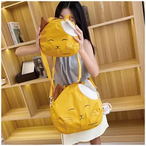 Detail of cute yellow cat canvas crossbody bags in large and small sizes with plush charm