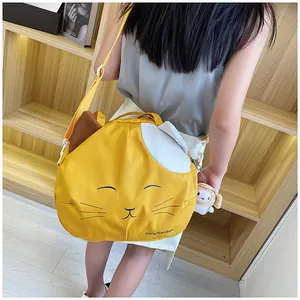 Detail of cute yellow cat canvas bag with cartoon embroidery and soft plush charm