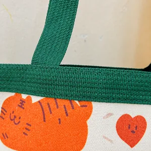 Detalle de costuras impecables en el bolso de lona con asa de nailon verde y estampado