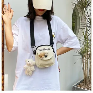 Detail of cream canvas crossbody bag featuring 3D bear motifs and adjustable strap