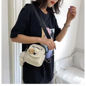 Detail of cute canvas crossbody bag with plush bear heads and a matching bear pendant