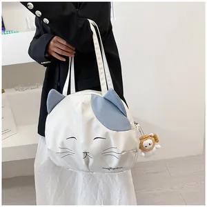 Detail of white cat-shaped canvas bag featuring blue ears and a cute fish doll pendant