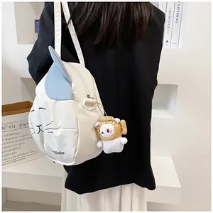 Cute white cat canvas bag with blue ears and plush pendant worn over a black blazer
